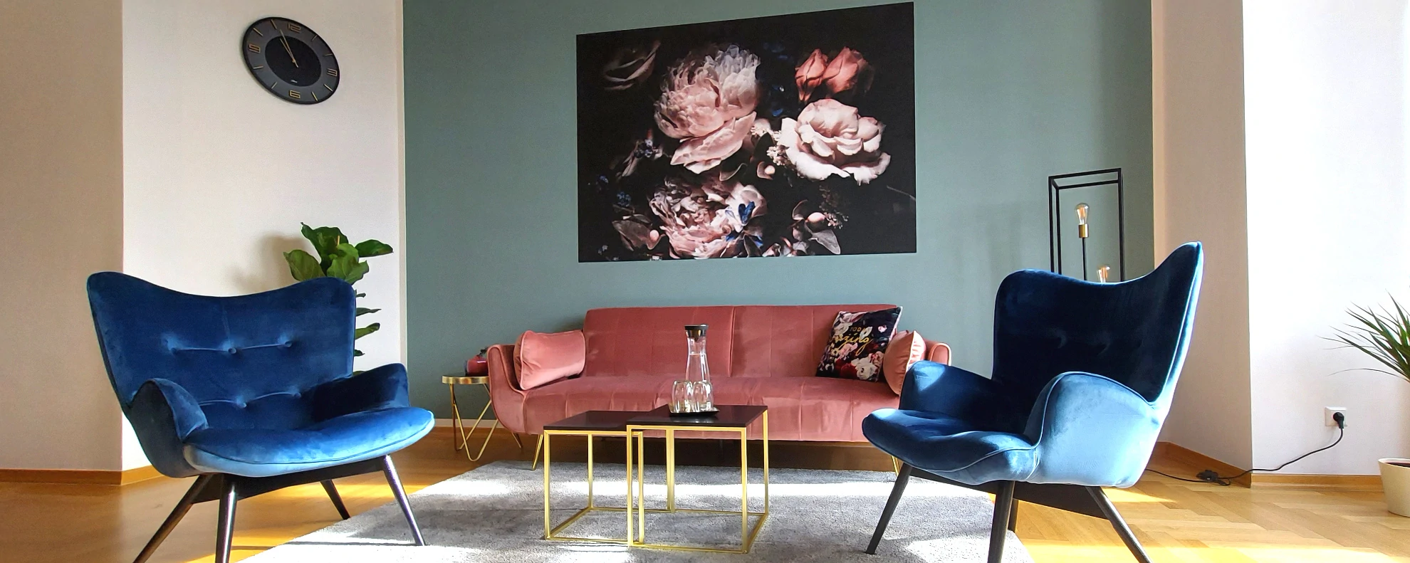 Impressionen aus den Praxisräumen: 2 blaue Sessel und ein Sofa vor einer dekorierten Wand
